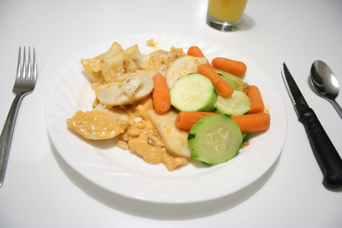 Perogies cooked with cheese sauce and onions, served with vegetables.