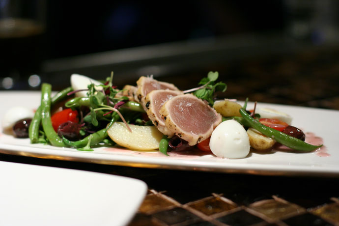 The entree sized version of the salad, La Petite Salad NiÃ§oise, with fresh micro greens, quail eggs, haricot vert niÃ§oise olives, fingerling potato, seared albacore tuna